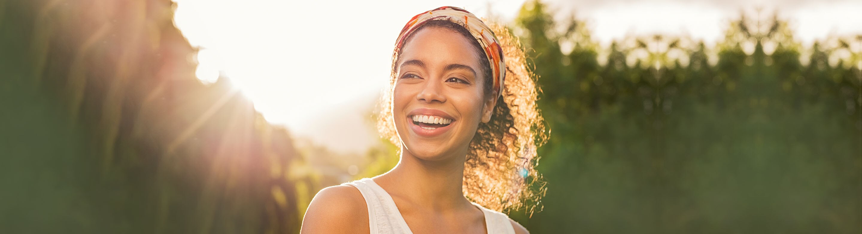 rutina-para-piel-suave mujer sonriente con un paño exfoliante espumoso en la mano tomando la ducha en casa
